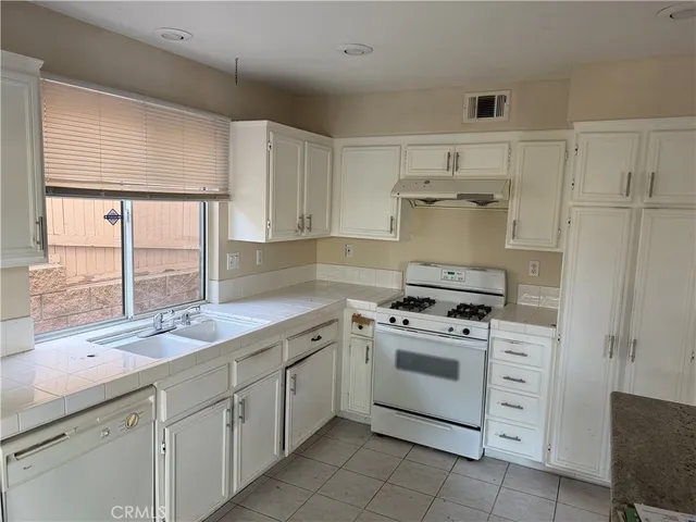 a kitchen with cabinets stainless steel appliances a sink and a window