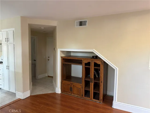 a view of an empty room with wooden floor and closet