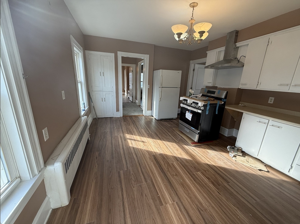 26 Lexington Street, Unit 2 Everett, MA 02149 - Photo 3 of 15 a kitchen with stainless steel appliances granite countertop a refrigerator a sink dishwasher a stove and white countertops with wooden floor