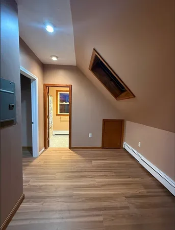 a view of an empty room with wooden floor and windows