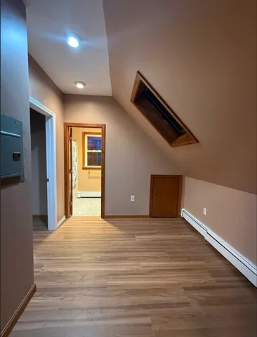 a view of an empty room with wooden floor and windows