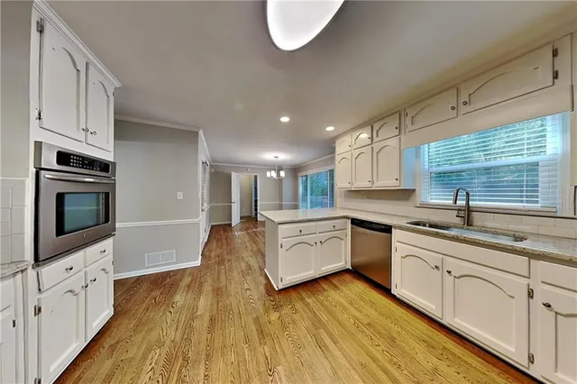 a large kitchen with cabinets wooden floor and stainless steel appliances