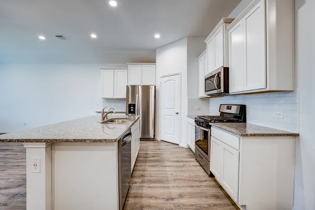 a kitchen with stainless steel appliances granite countertop a stove a sink and a refrigerator