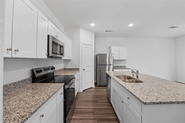 a kitchen with granite countertop white cabinets and stainless steel appliances