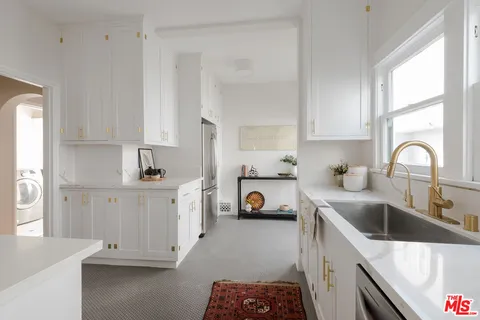 a kitchen with white cabinets and sink