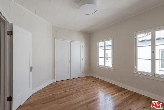 a view of empty room with wooden floor and fan