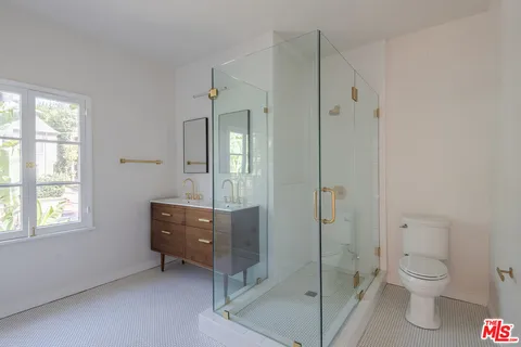 a bathroom with a toilet shower vanity and a sink
