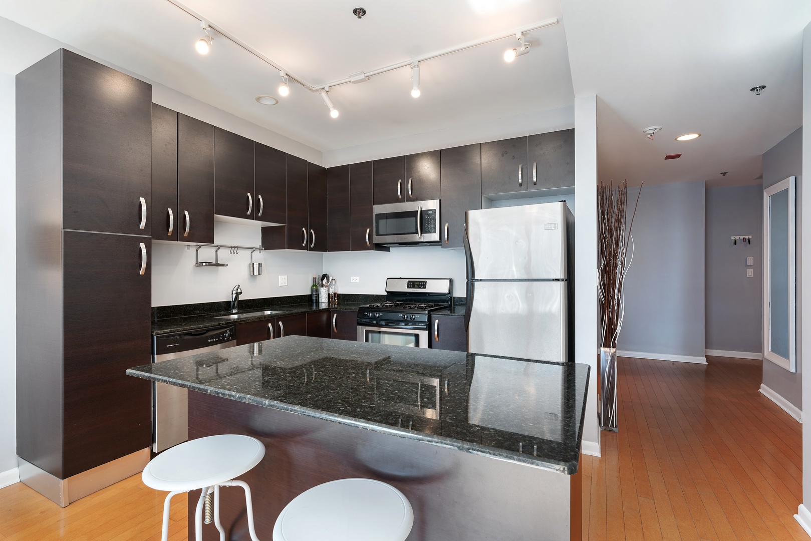 225 South Sangamon Street, Unit 402 Chicago, IL 60607 - Photo 5 of 12 a kitchen with stainless steel appliances granite countertop a refrigerator a sink a stove a microwave oven with white cabinets and chairs