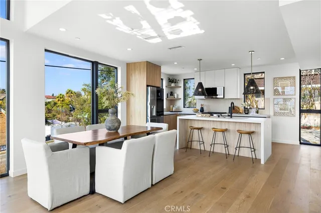 a kitchen with kitchen island stainless steel appliances a stove a sink a refrigerator and a dining table