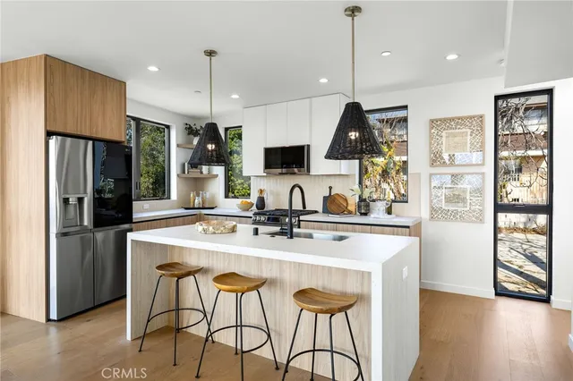 a kitchen with stainless steel appliances granite countertop a sink a stove a refrigerator cabinets and wooden floor