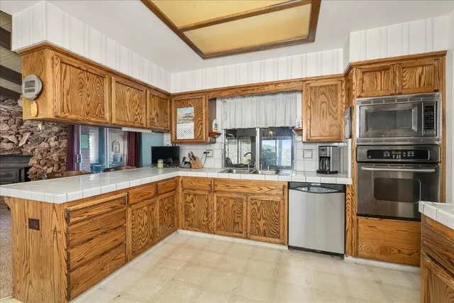 a kitchen with stainless steel appliances granite countertop a stove top oven a sink dishwasher and cabinets with wooden floor