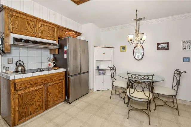 a kitchen with stainless steel appliances granite countertop a dining table chairs cabinets and a sink