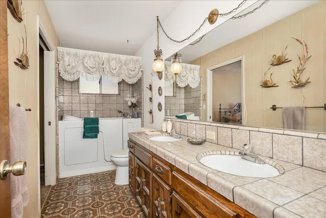 a bathroom with a granite countertop double vanity sink mirror and shower