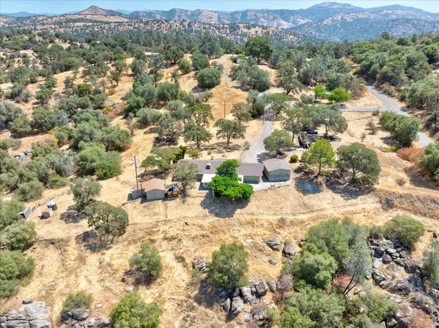 an aerial view of residential house with yard and mountain view in back