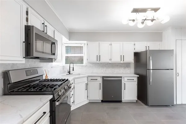 a kitchen with stainless steel appliances granite countertop a stove a refrigerator a sink a stove and white cabinets