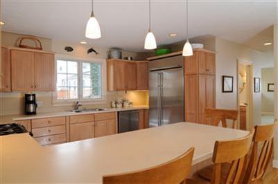 127 West Bay Road, Unit A Osterville, MA 02655 - Photo 7 of 11 a large kitchen with stainless steel appliances kitchen island granite countertop a refrigerator a stove a sink a dining table and chairs with wooden floor