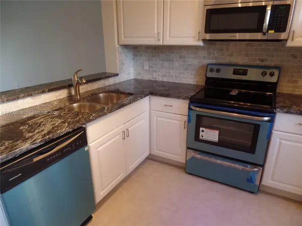 a kitchen with granite countertop a stove top oven microwave and cabinets