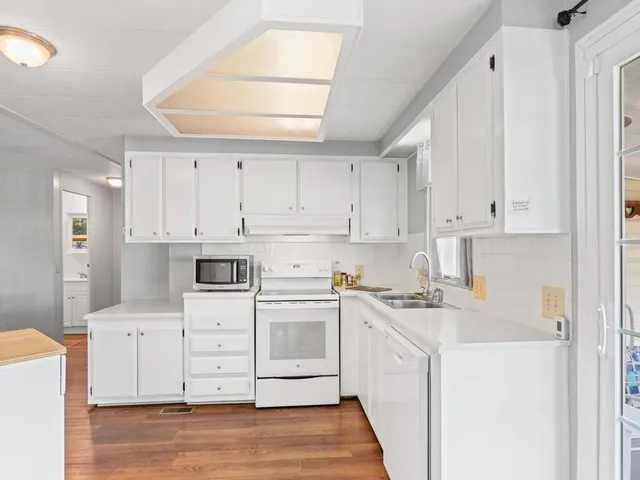 a kitchen with cabinets appliances and a wooden floor