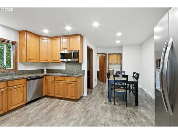 a kitchen with stainless steel appliances granite countertop wooden cabinets a dining table and chairs
