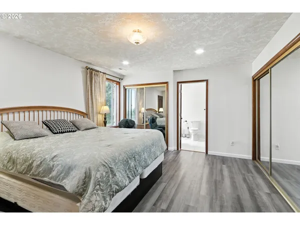 a spacious bedroom with a bed and a dresser with wooden floor