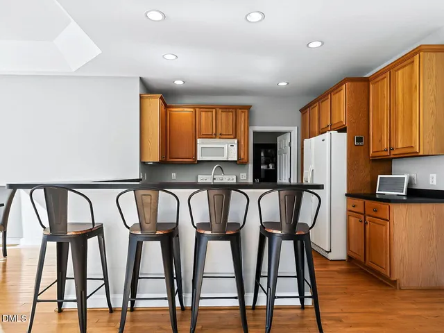 a kitchen with stainless steel appliances granite countertop wooden floor furniture and a refrigerator
