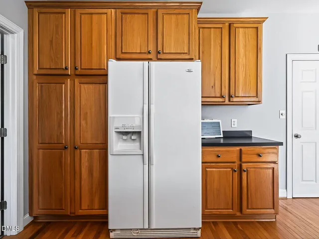 a view of a kitchen with refrigerator and wooden cabinets