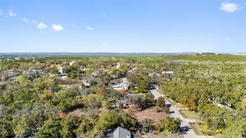 an aerial view of residential houses with outdoor space and trees