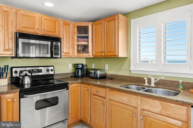a kitchen with granite countertop a sink a stove and cabinets