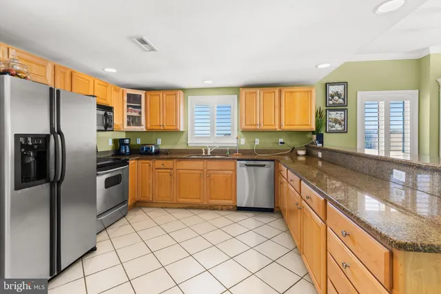 a kitchen with stainless steel appliances granite countertop a sink counter space cabinets and a large window