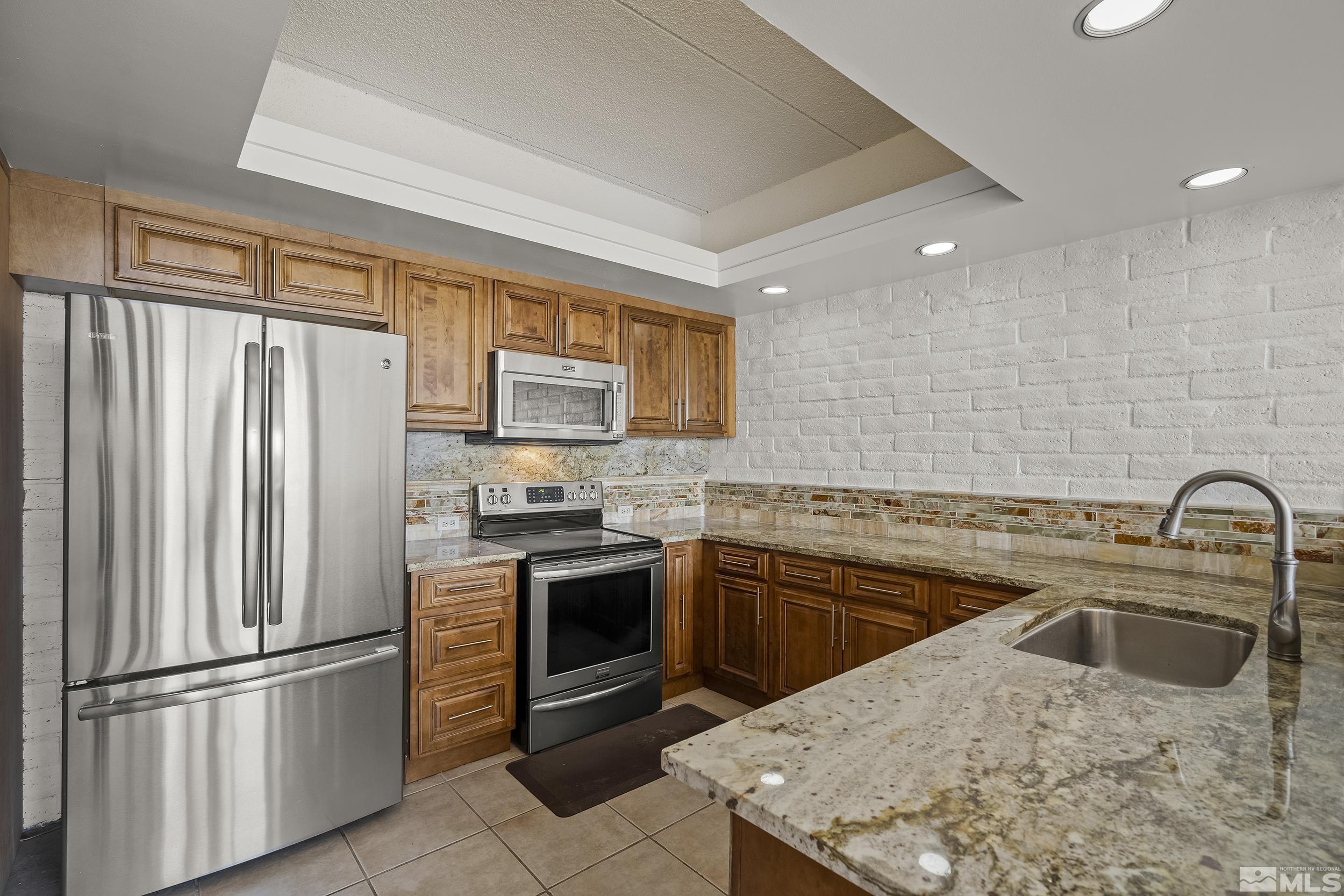 1200 Riverside Drive, Unit #1209 Reno, NV 89503 - Photo 12 of 35 a kitchen with stainless steel appliances granite countertop a refrigerator sink stove and oven