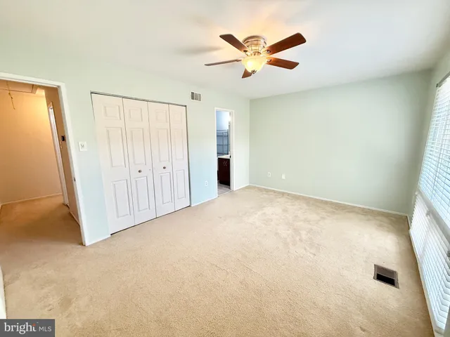 an empty room with closet and a chandelier fan