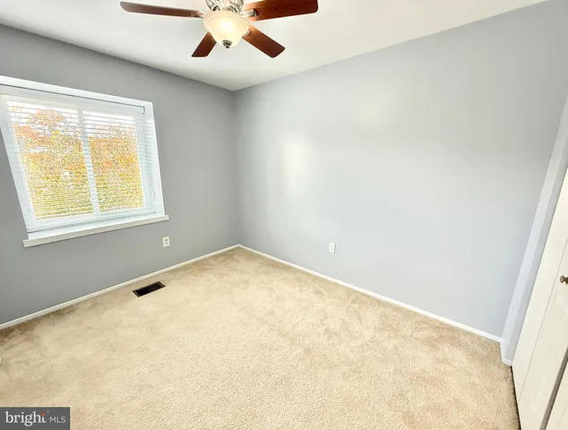 an empty room with a window and ceiling fan
