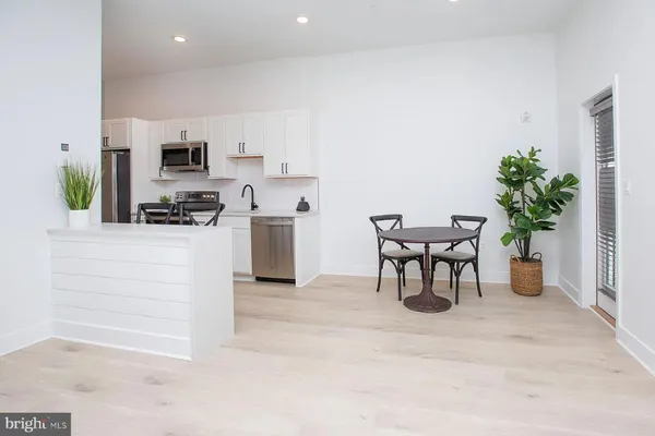 a living room with furniture a potted plant and kitchen view