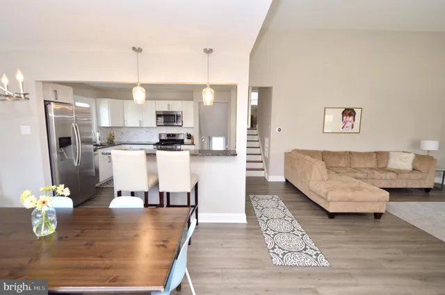 a living room with stainless steel appliances furniture a rug and a kitchen view