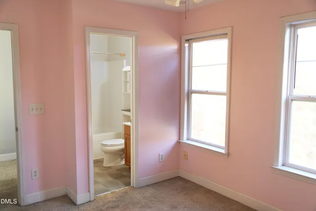 an empty room with a fan & a window