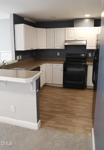a kitchen with granite countertop white cabinets and stainless steel appliances