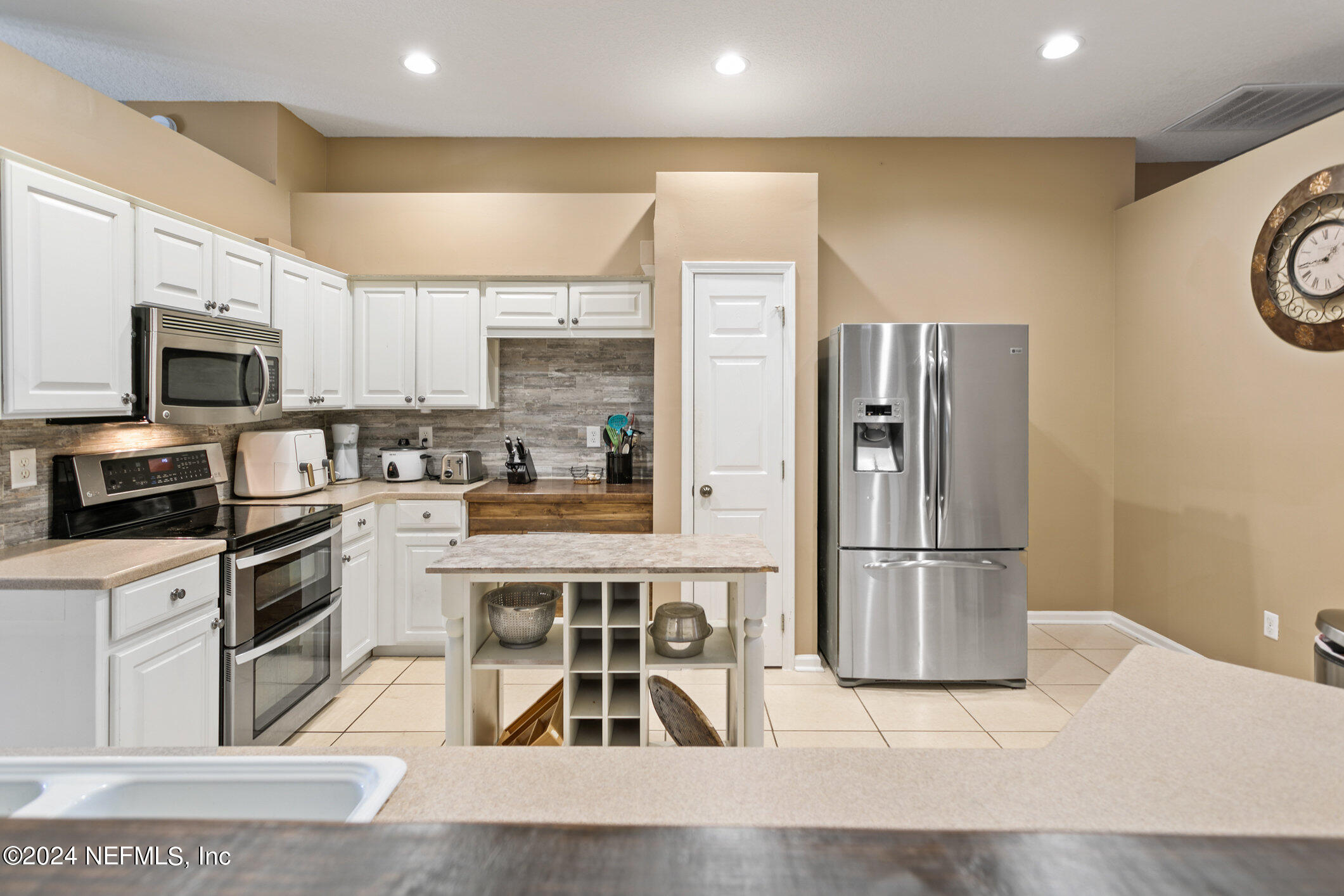 809 Mill Pond Court St. Johns, FL 32259 - Photo 9 of 50 a kitchen with stainless steel appliances kitchen island granite countertop a refrigerator a stove a sink and white cabinets with wooden floor