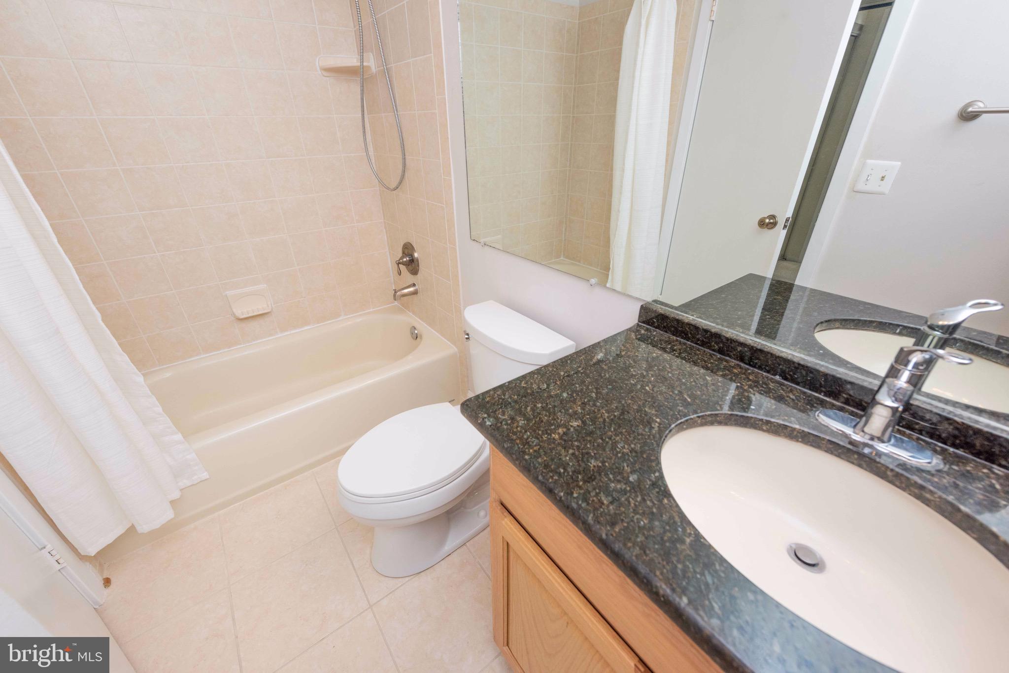 11708 Summerchase Circle, Unit 1708E Reston, VA 20194 - Photo 12 of 17 a bathroom with a granite countertop sink toilet and shower