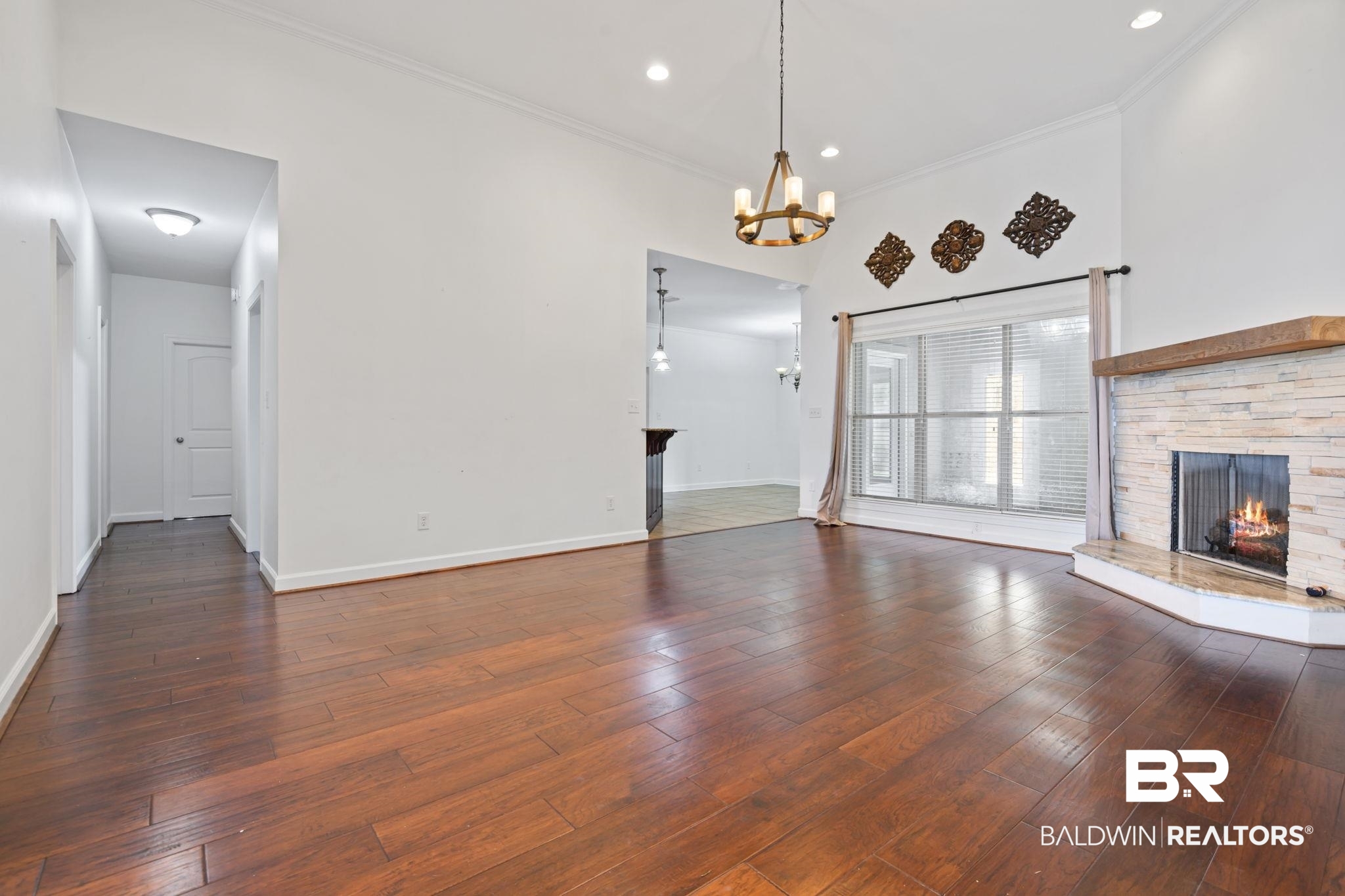 9730 Harmony Ridge Circle West Semmes, AL 36575 - Photo 3 of 38 Unfurnished living room featuring a chandelier, a fireplace, baseboards, hardwood / wood-style flooring, and crown molding