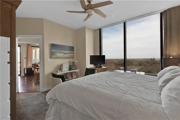 a bedroom with a bed a chandelier with a flat screen tv and a large window