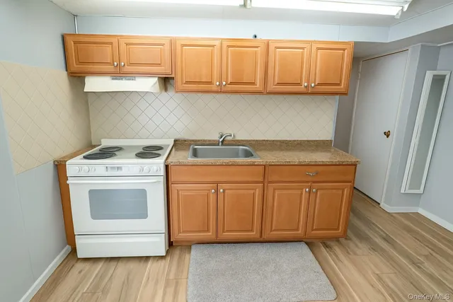 a kitchen with granite countertop a sink a stove and cabinets