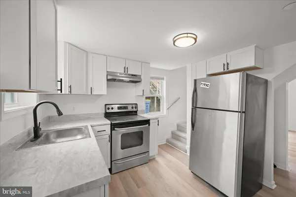 a kitchen with stainless steel appliances a refrigerator sink and white cabinets