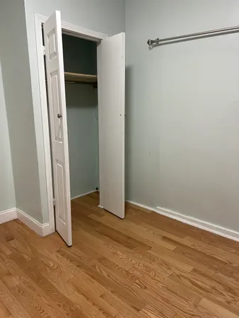 a view of an empty room with wooden floor and closet