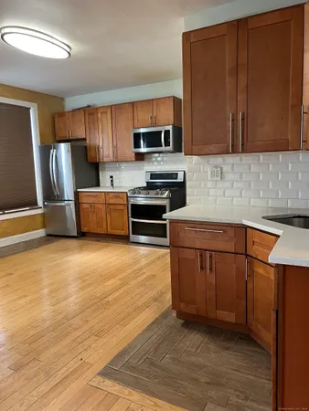 a kitchen with stainless steel appliances granite countertop a stove top oven a sink dishwasher and a refrigerator with wooden cabinets