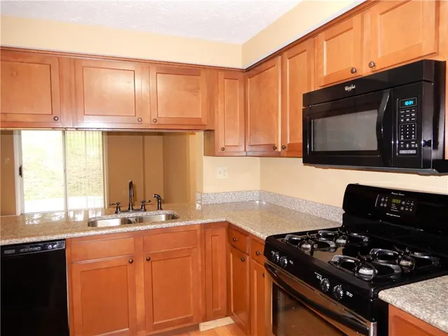a kitchen with granite countertop a sink stove and cabinets