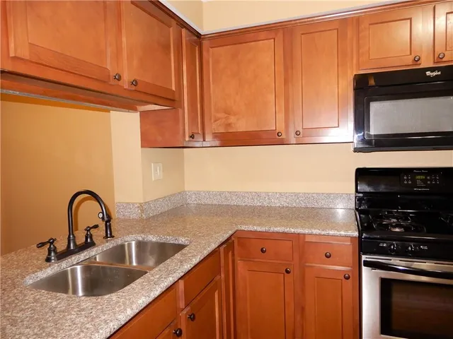 a kitchen with granite countertop a sink stainless steel appliances and cabinets
