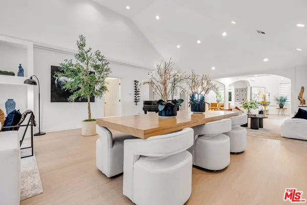 a dining hall with stainless steel appliances kitchen island granite countertop a living room and couches with wooden floor