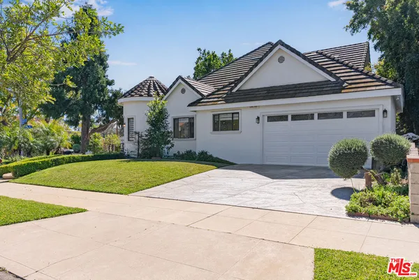 a front view of a house with garage and plants