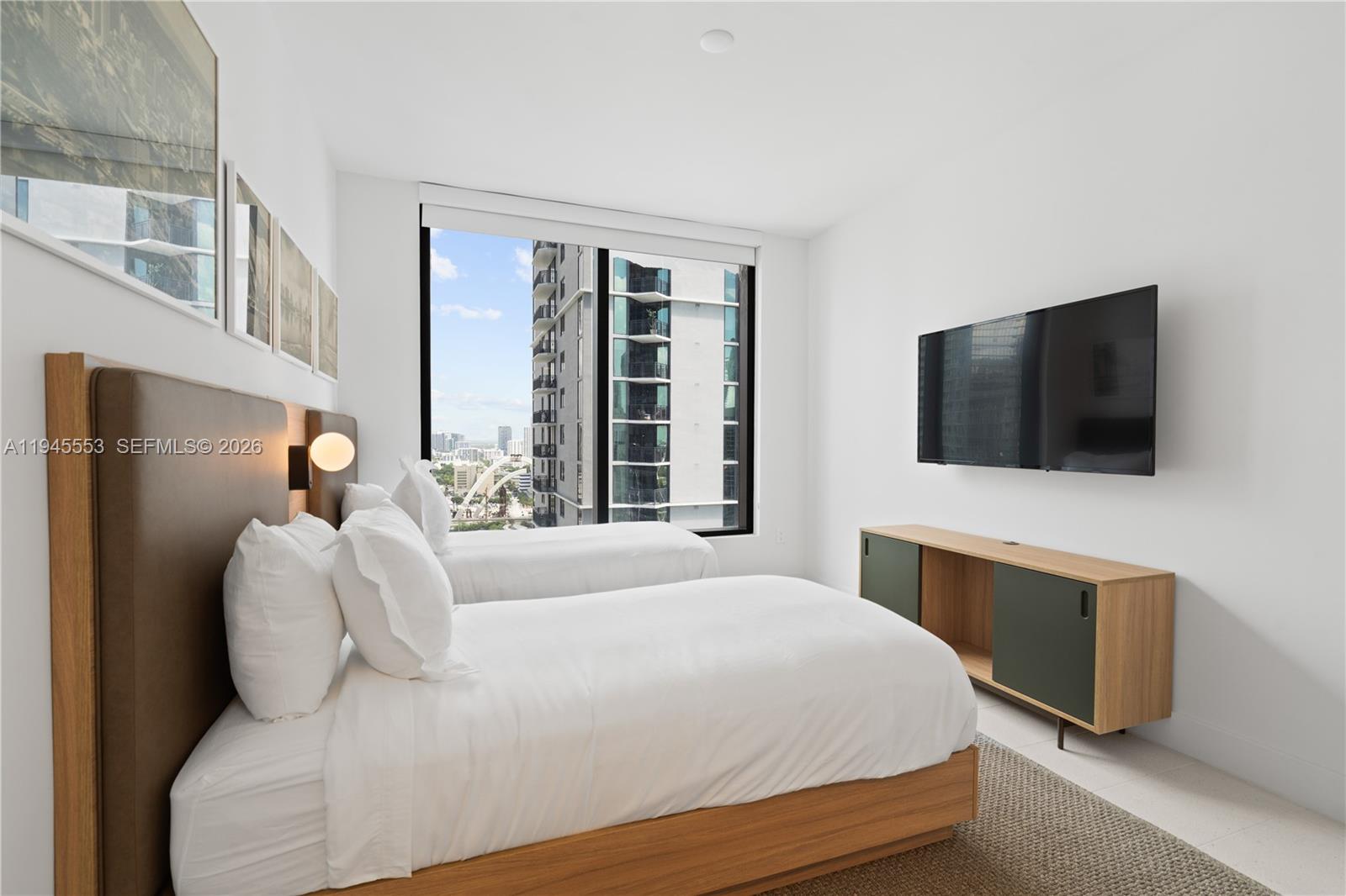 159 Northeast 6th Street, Unit 2415 Miami, FL 33132 - Photo 33 of 42 a bedroom with a bed and a flat tv screen on dresser