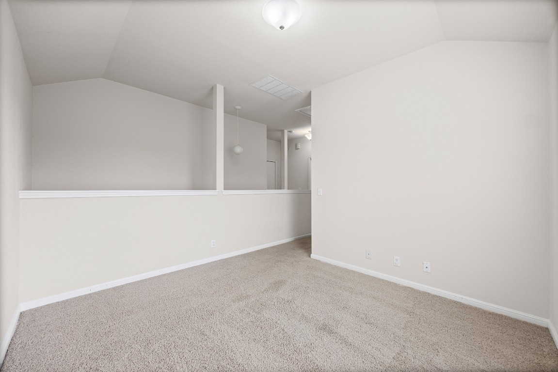 336 Celery Loop Austin, TX 78748 - Photo 12 of 32 Carpeted empty room with vaulted ceiling and baseboards